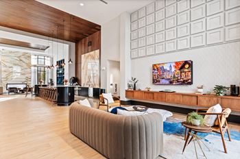 A modern living room with a large sofa and a TV on the wall.